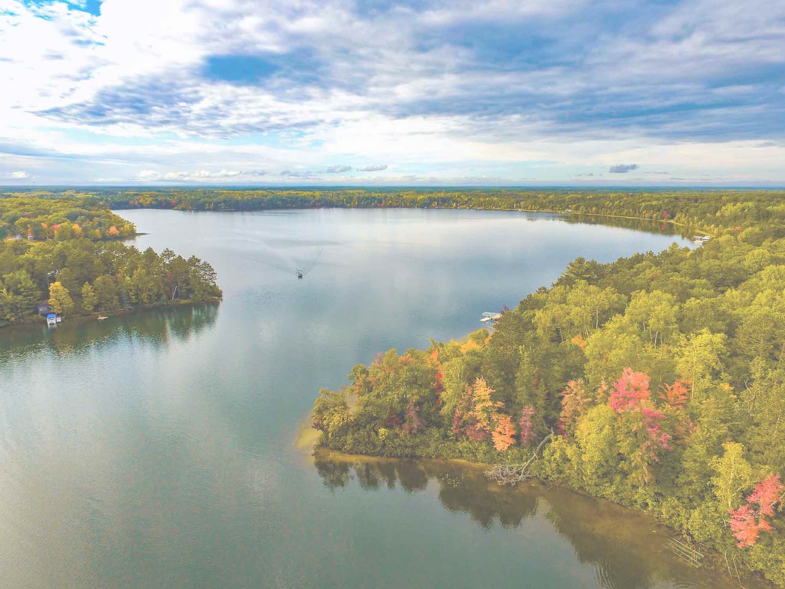 An aerial view of a Wisconsin lake ringed by autumn forest, in the Waukesha County area